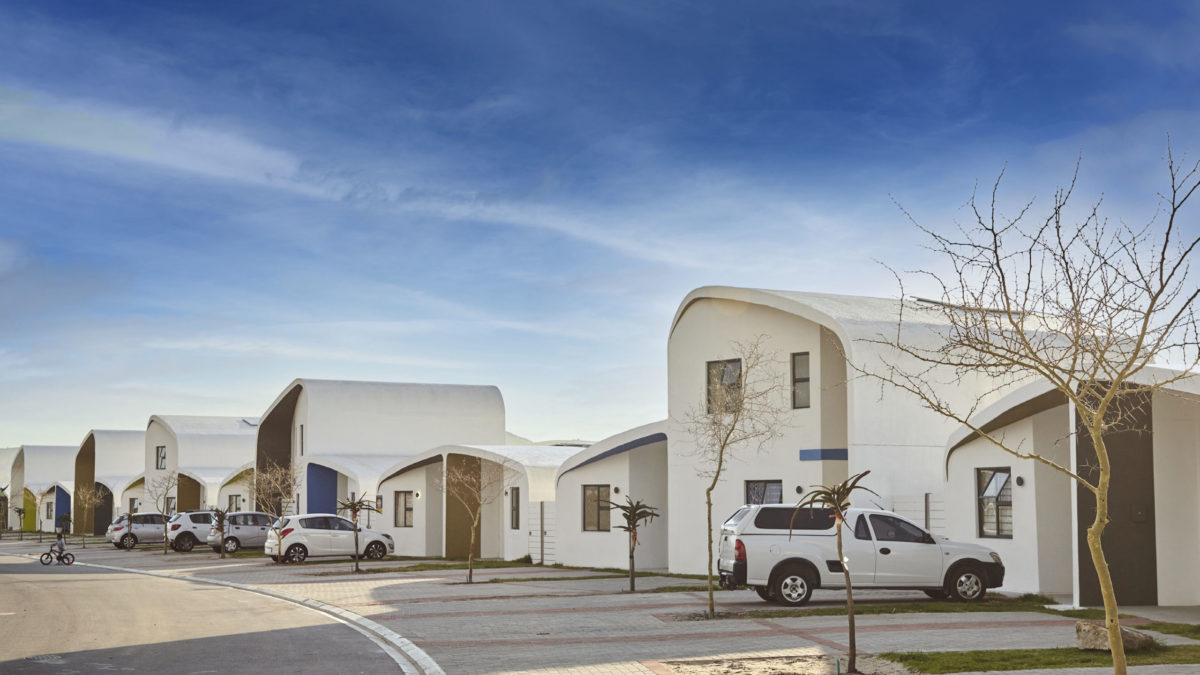 A street lined with Citra sustainable eHomes, showing multiple modern, energy-efficient houses with a blue sky in the background